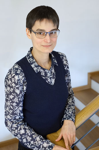 Heike Heinz, dunkle kurze Haare, Brille, gemusterte Bluse, dunkelblauer Pullunder