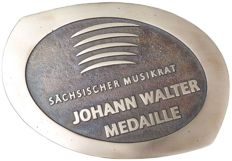 Die neue Johann Walter Medaille ist eine Bronzemedaille mit dem Logo des Sächsischen Musikrates, fünf Halbbögen, der Schrift Johann Walter Medaille und Sächsischer Musikrat