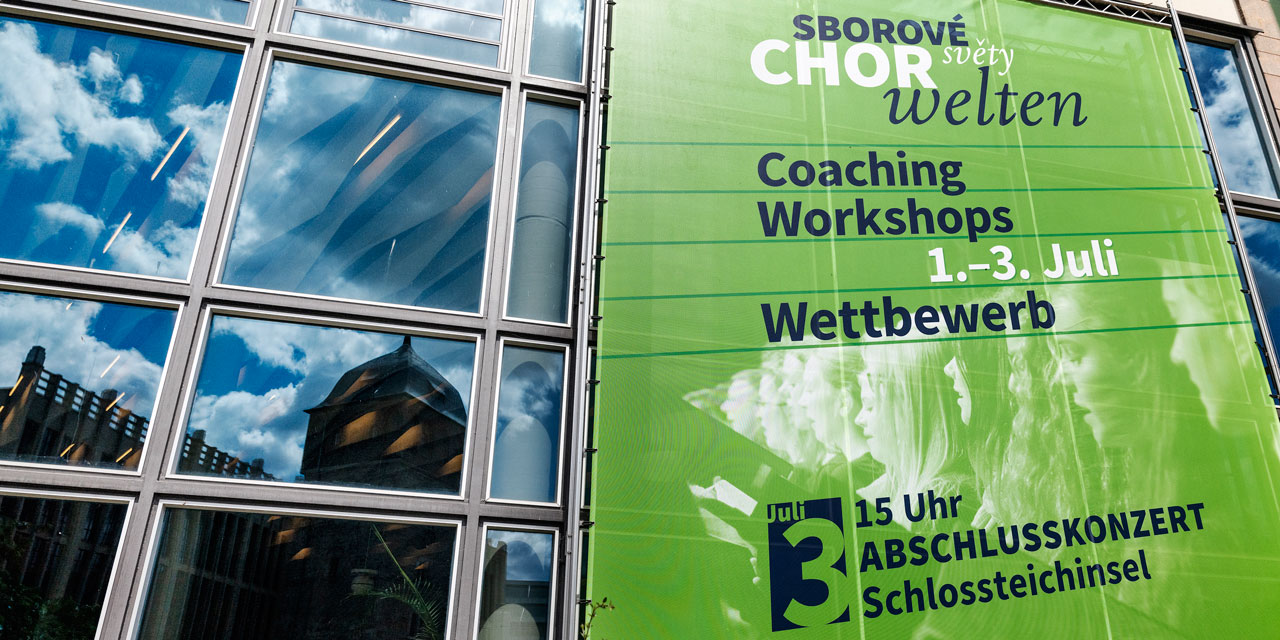 Das grüne Banner für Chorwelten hängt außen an der Stadthalle 