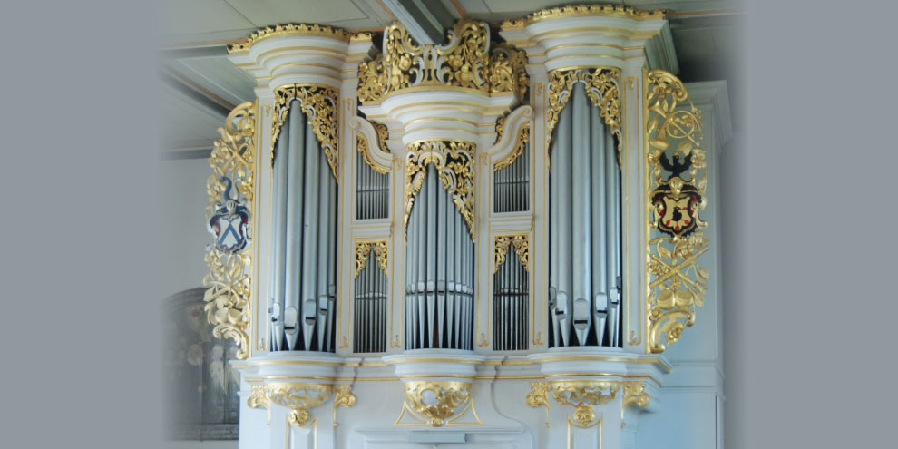 Die Schramm-Orgel in Stangengrün hat sieben sichtbare Fächer mit Orgelpfeifen unterschiedlicher Größe. Die Orgel ist weiß und besitzt zahllose goldene Verzierungen, links und rechts neben der Orgel sind in diese je ein Wappen eingearbeitet.