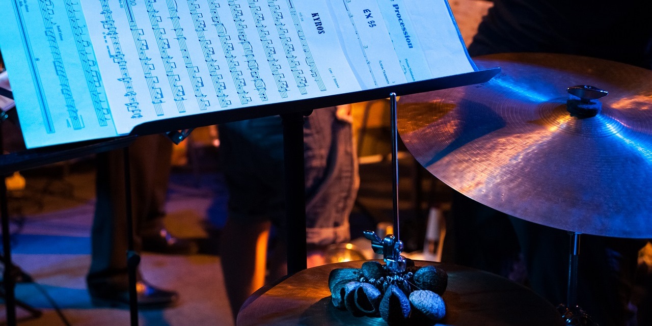 Eine Nahaufnahme der Becken eines Schlagzeugs und einem Notenständer mit Noten darauf