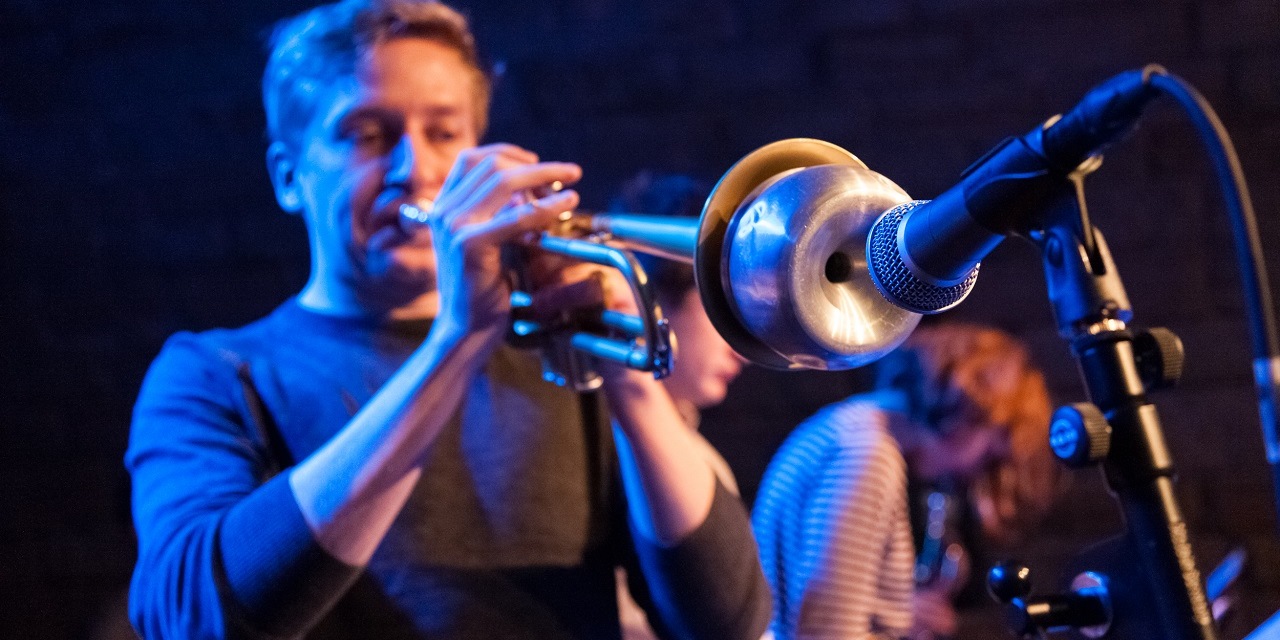 Ein Mann spielt Trompete in ein Mikrophon