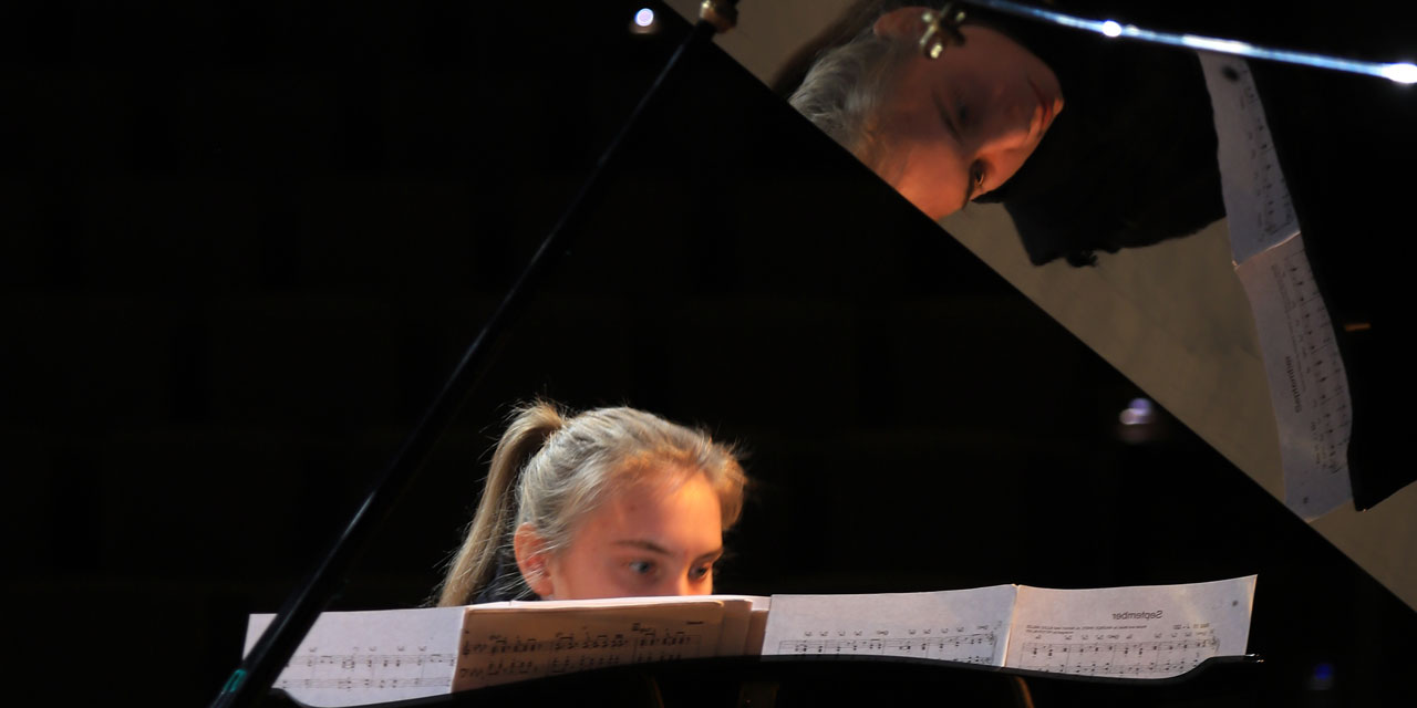 Eine Pianistin spielt konzentriert ihr Instrument.