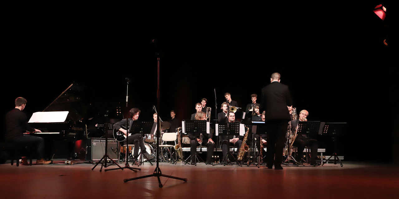 Ein Orchester mit Dirigent musiziert zusammen.