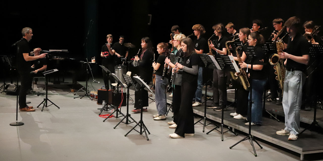Ein Dirigent dirigiert das vor ihm stehende Jugendorchester.