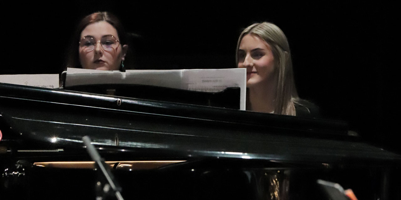 Zwei Pianistinnen sitzen an einem Flügel. Sie blicken konzentriert in die Noten.