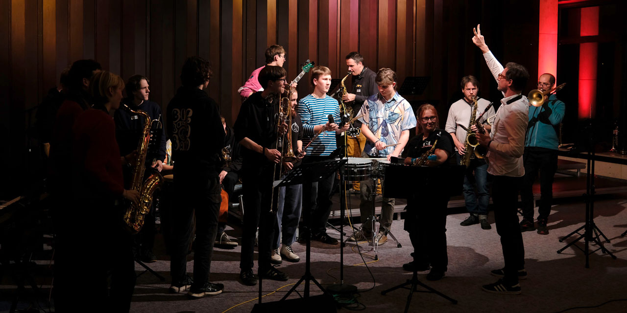 Mehrere Musiker und Musikerinnen musizieren in einer abendlichen Session.