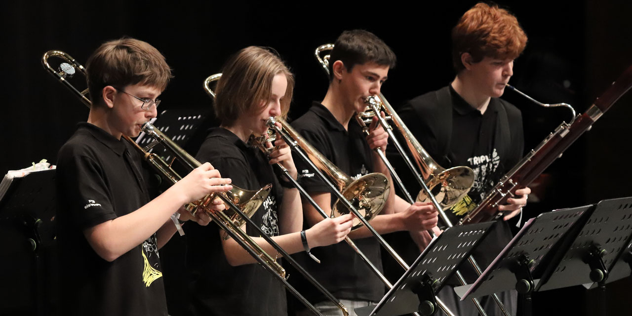 Drei Jugendliche spielen Posaune und ein Jugendlicher spielt Fagott.