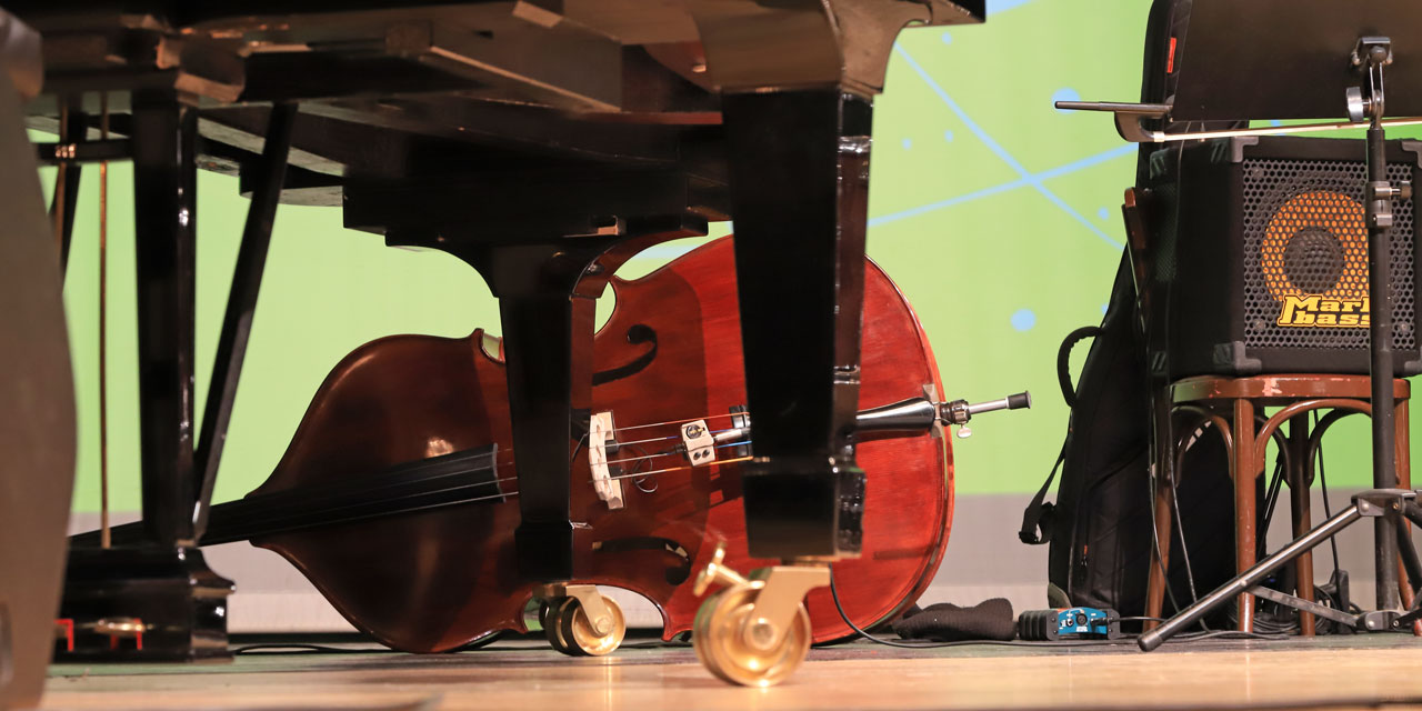Ein Kontrabass liegt auf der Seite hinter einem Klavier.