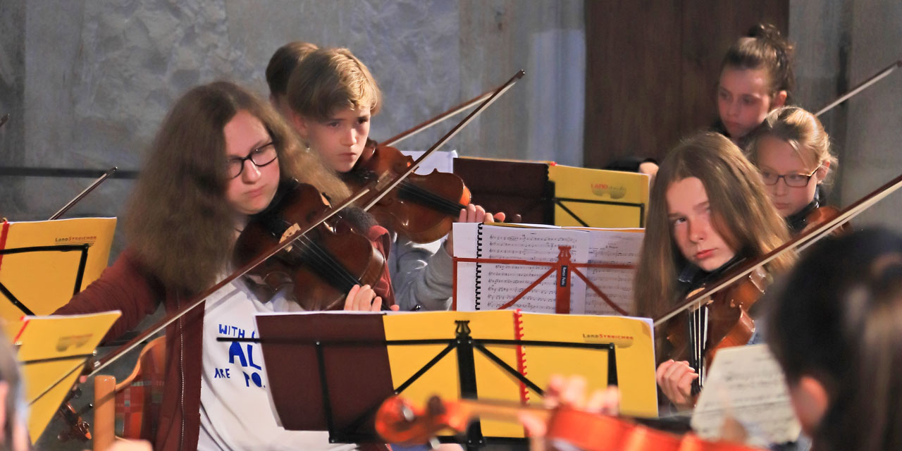 Sechs Kinder beim Proben spielen ihre Violinen.