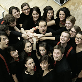 Ein Chor der einen Kreis um ein Chormitglied bildet von oben fotografiert