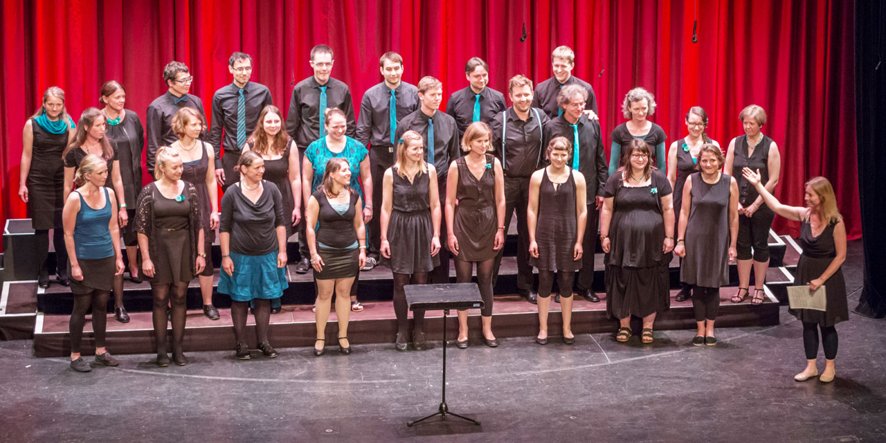 Eine Chorleiterin präsentiert stolz ihren Chor auf der Bühne