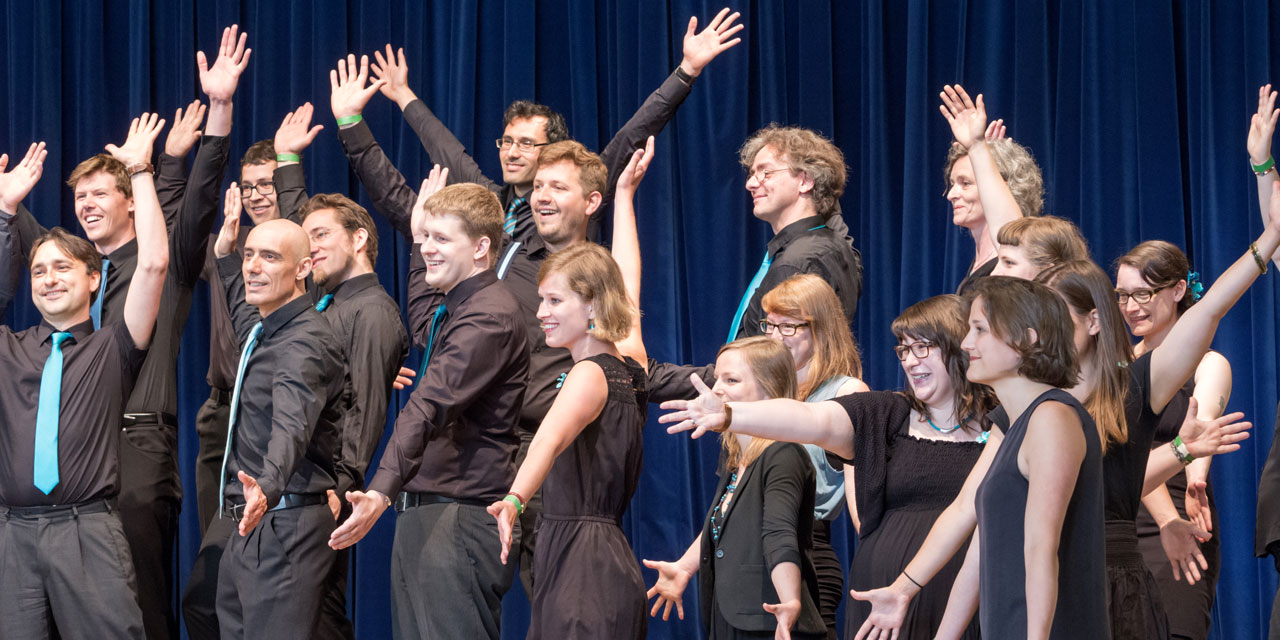 Chorsänger erheben die Arme die Männer tragen hellblaue Krawatten