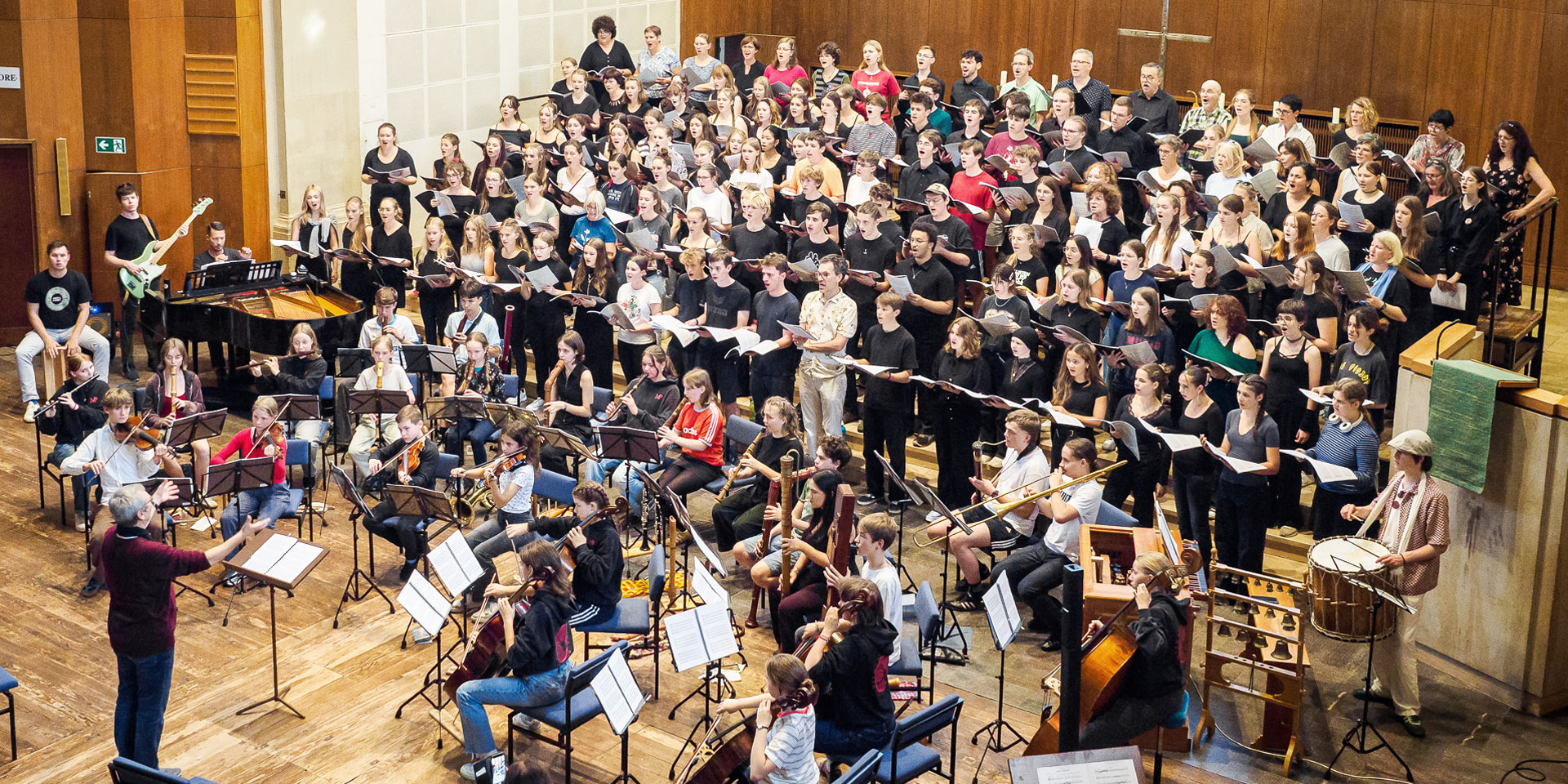 Ein großer Chor mit Jugendlichen in der Lukaskirche Dresden von der rechten Empore aus fotografiert. Vor dem Chor sitzt musizierend ein Jugendensemble 